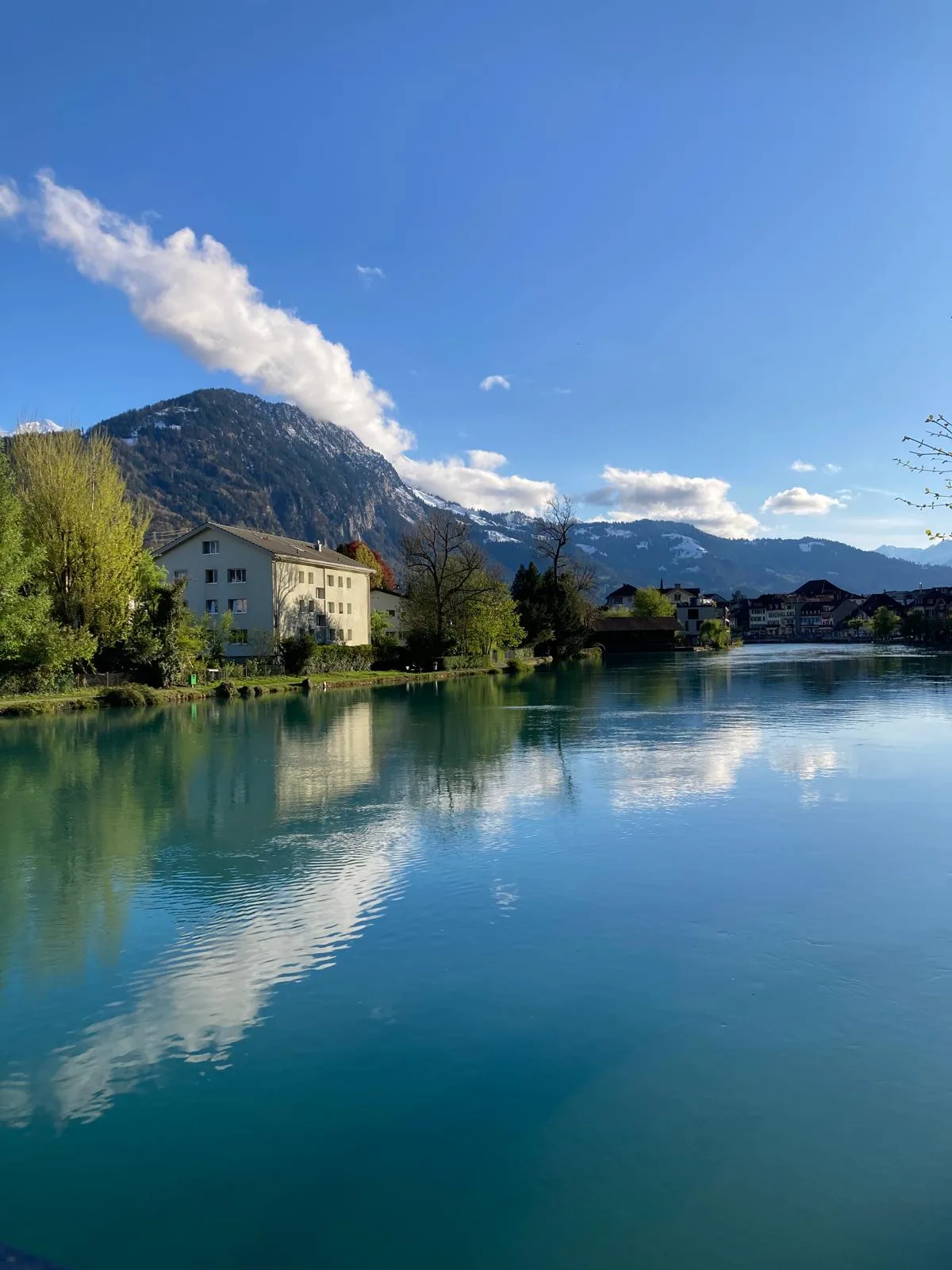 Calm river reflecting Swiss alpine peaks and a lakeside town